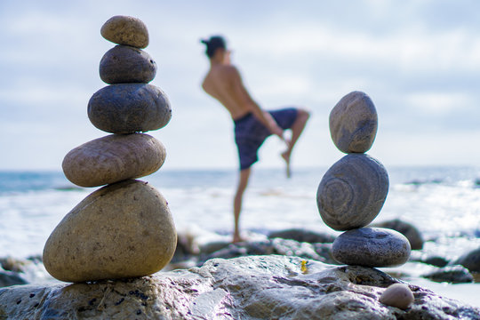 Man Kneeing With Stacking Rocks By The Ocean. Beautiful