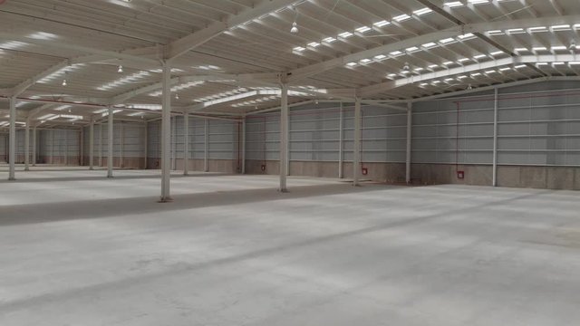 Aerial interior clip of an empty warehouse with camera moving forward and rotating 360 degrees