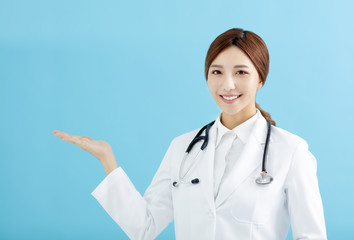 Smiling female doctor pointing with finger on blue background