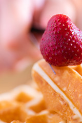 woman hands prepare waffle for serving process.waffle made from dough and batter.tasty dessert sweets waffle served on daylight in cafe bokeh background.waffle with strawberry on black plate.