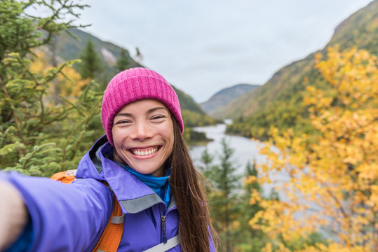 Selfie Asian girl hiking in autumn nature mountain camping outdoor fall lifestyle. Woman taking photo with mobile phone online.