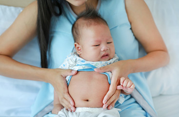 Close-up hands of mother touching and take care infant with pain in her Stomach.