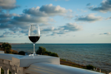 Glass of red wine on the beach at colorful sunset
