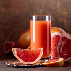 Glass of fresh grapefruit juice and cut fruits .
