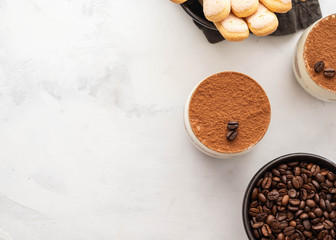 Traditional Italian dessert tiramisu in a glass on a white stone background. Copy space.