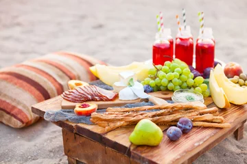 Fototapete Picknick Picknick am Strand bei Sonnenuntergang im Boho-Stil. Konzept im Freien abends gesundes Abendessen mit Obst und Saft