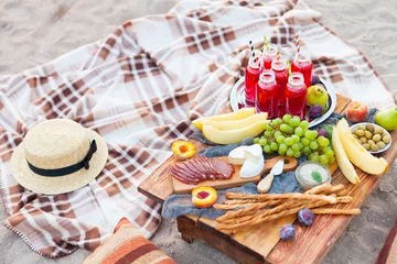 Crédence de cuisine en verre imprimé Pique-nique Pique-nique sur la plage au coucher du soleil dans le style bohème. Concept de dîner sain en plein air avec des fruits et des jus de fruits