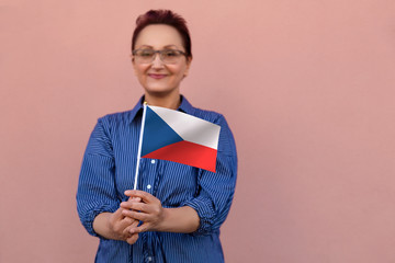 Czech flag. Woman holding the flag of the Czech Republic. Nice portrait of middle aged lady 40 50 years old with a national flag over pink wall background.