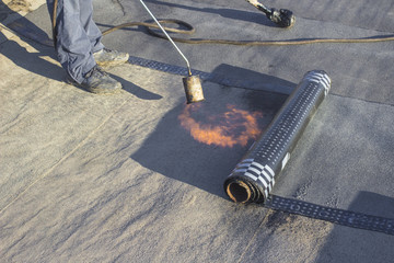 Roll roofing Installation with propane blowtorch during construction works