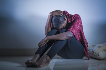 lifestyle indoors portrait of young sad and depressed black african American woman sitting at home floor feeling desperate and worried suffering pain