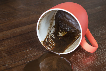 Spilled coffee from a red cup. Coffee grounds on a wooden table. Soft focus