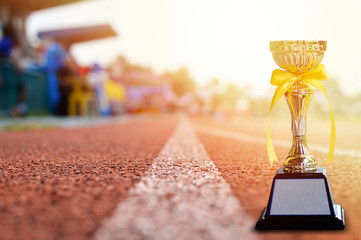 Golden trophy with yellow bow tie on running track for business success concept.