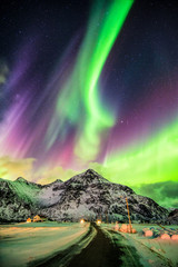 Aurora Borealis (Northern lights) explosion over mountains and rural road