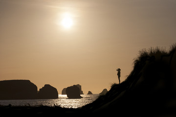 silueta de chica mirando al horizonte en la costa al atardecer