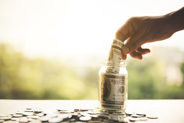 close up hand putting banknote into glass bottle.Business, finance, savings or management money,...
