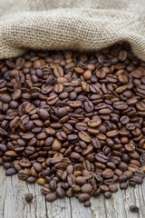 Coffee beans in coffee burlap bag on wooden surface