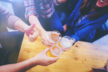 Group of friends clinking the glasses of beer in nightclub. Party after working