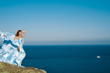 Fototapeta na wymiar girl in a blue dress and flying on sea