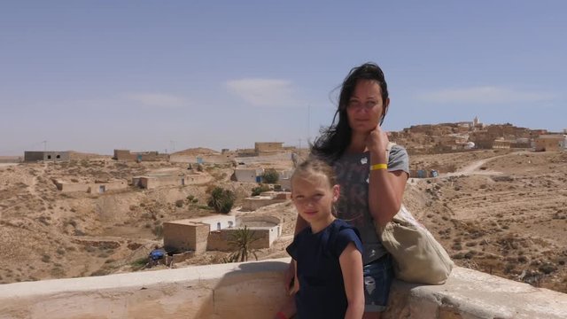 Young mother and daughter posing for photo on bedouin village background