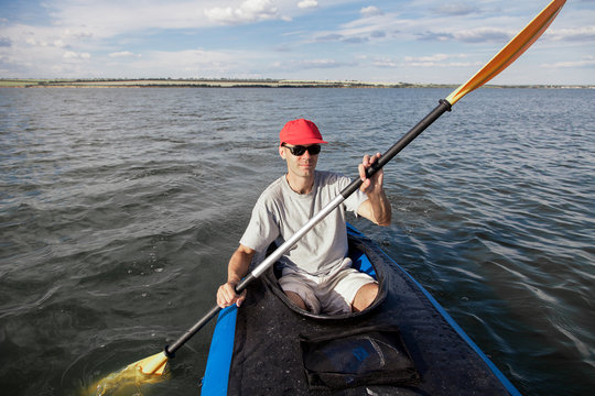  A man on a kayak floats on the lake. Sports on the water. The athlete is holding an oar.