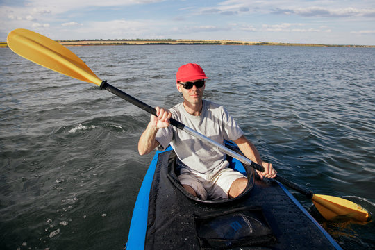 A man on a kayak floats on the lake. Sports on the water. The athlete is holding an oar.