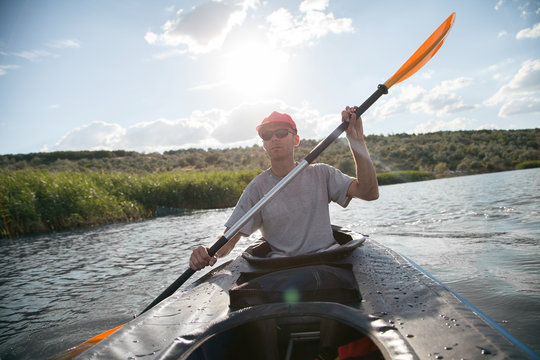  A man on a kayak floats on the lake. Sports on the water. The athlete is holding an oar.