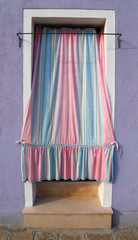 Fototapeta na wymiar pink and blue curtains in front of the entrance of the house