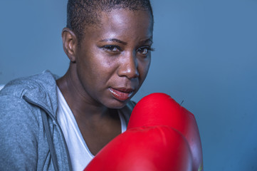  face portrait of young angry and defiant black african American sport woman in boxing gloves...