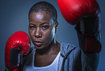  face portrait of young angry and defiant black afro American sport woman in boxing gloves training...