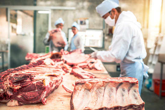 Butcher Group And Friends Works In A Slaughterhouse And Cuts Raw Beef