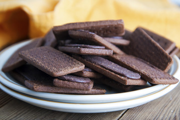 Chocolate cookies or biscuits and cream in, on wooden background. Close up sweet unhealthy snack or kids or adults.