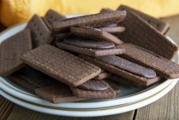 Chocolate cookies or biscuits and cream in, on wooden background. Close up sweet unhealthy snack or kids or adults.