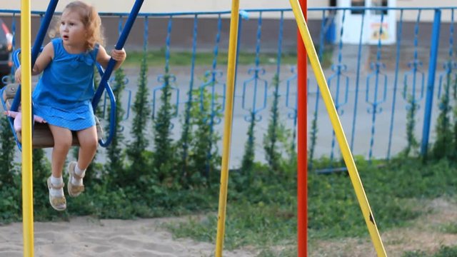 Child girl swings on a swing in the playground