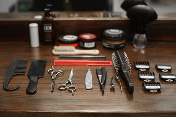 Tools for a hairdresser on a dark wooden table at a barber shop - scissors, nozzles, combs and...