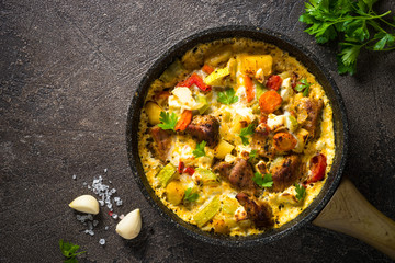 Frittata with meat and vegetables on dark background.