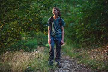 Young man in bandana hiking on forest path.
