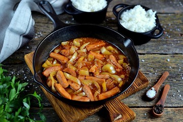 Pork meat stewed with sweet pepper, onions and carrots with tomato sauce in a frying pan. 