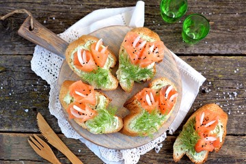 Homemade sandwiches with avocado pasta and lightly salted salmon on a cutting board. Rustic style.