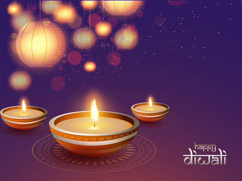 Illuminated oil lamps (Diya) on shiny background decorated with hanging paper lanterns (lamps) and blurred lighting effect for Diwali festival celebration.