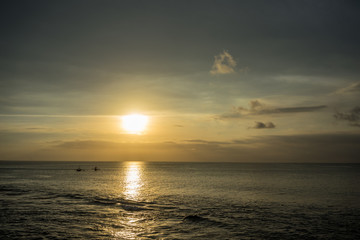 Fototapeta na wymiar Ocean Sunset in Bali, Indonesia with small boats on water