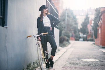 Woman standing on the street next to her fixie bicycle.