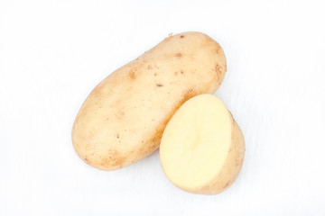 New harvest. Potatoes from the own garden. Ecologically, biological, healthy, delicious. Stack of brown/ yellow potatoes with half of it. Young potato isolated on white background. Closeup. Top view.