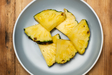 Piña en rodajas sobre un plato gris. Vista superior