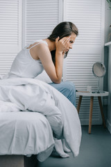 side view of young woman in pajamas suffering from headache on bed