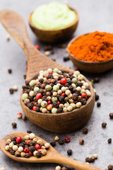 Peppercorn mix in a wooden bowl on grey table.