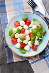 Delicious caprese salad with ripe cherry tomatoes and mini mozzarella cheese balls with fresh basil leaves.