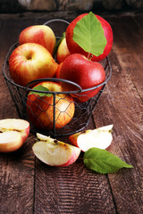 Ripe red apples with leaves on wooden background