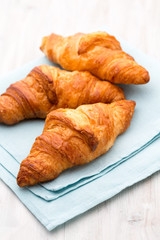 Tasty buttery croissants on old wooden table.