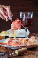 Prosciutto with melon on a plate. Preparation of cold snacks to red wine.