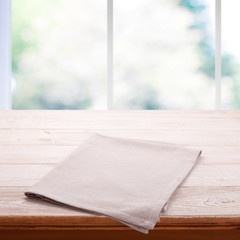 Empty wooden table with tablecloth. Napkin close up top view mock up. Kitchen rustic background with window.